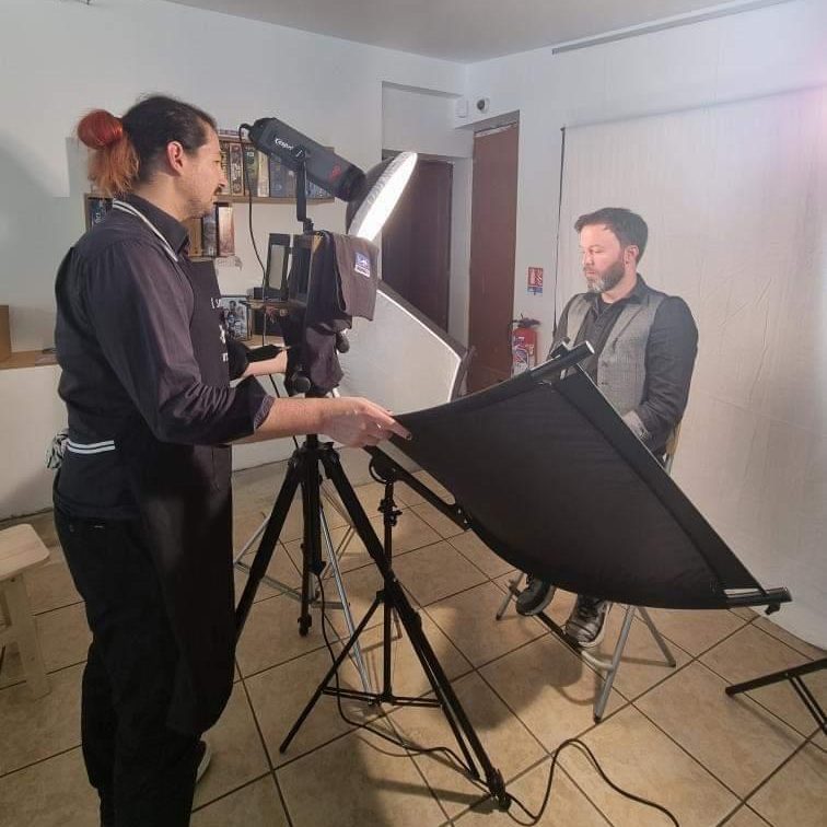 Photo du photographe en train d'ajuster du matériel d'éclairage et de la personne sujet assise sur un tabouret