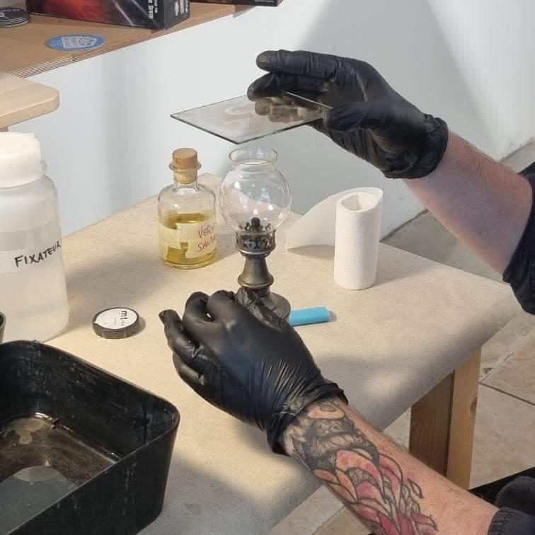 Photo de mains gantées en train de tenir une plaque de verre au dessus d'une lampe à alcool